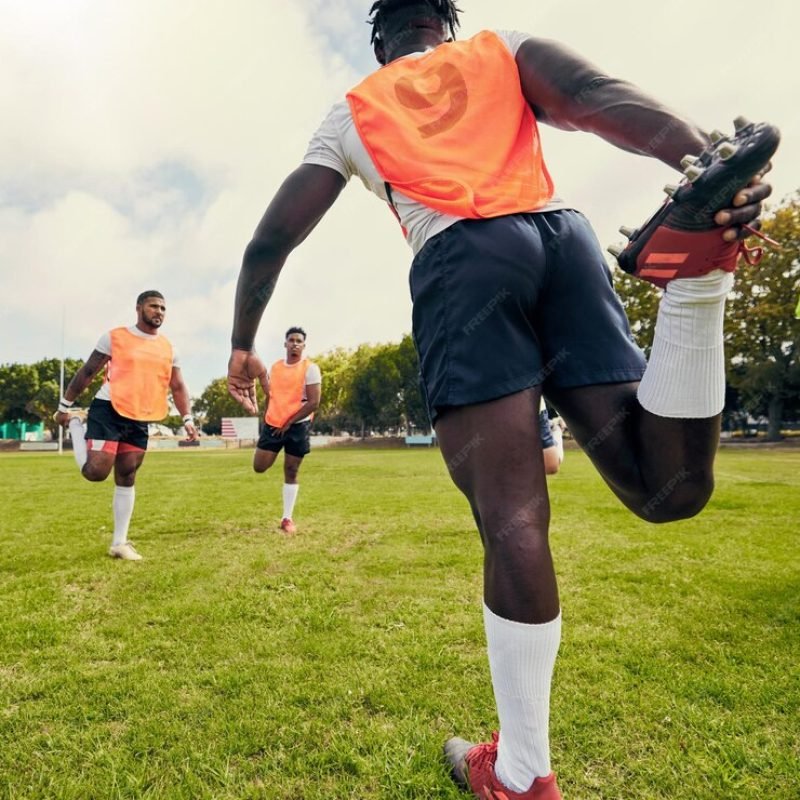 sports-men-training-outdoor-rugby-grass-field-with-team-stretching-legs-as-warm-up-athlete-group-together-fitness-exercise-workout-professional-sport-with-coach-teamwork_590464-169091